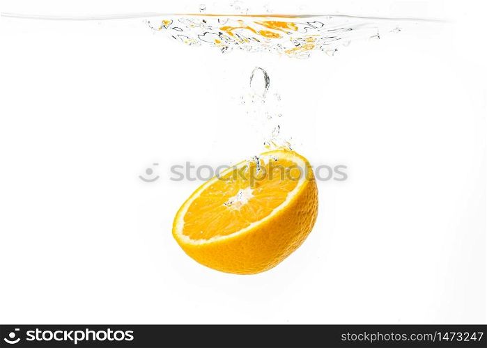 Fresh ripe half of orange fruit sinking in the clear water, isolated on white background. Health food concept. Fresh ripe half of orange fruit sinking in the clear water, isolated on white background