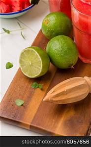 Fresh ripe limes and juicer on wooden table.