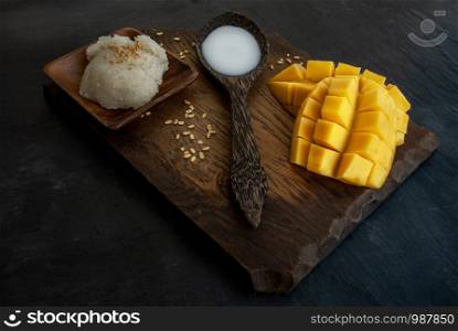 Fresh ripe mango (Barracuda mango) and sticky rice with coconut milk, authentic Thai dessert, popular traditional dessert of Thailand. Oblique view from the top.