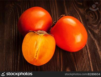 Fresh ripe orange persimmon and slice on a wooden background