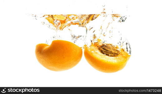 Fresh ripe organic apricot split in half falling in the clear water, isolated on white background. Fresh ripe peach split in half falling in the clear water