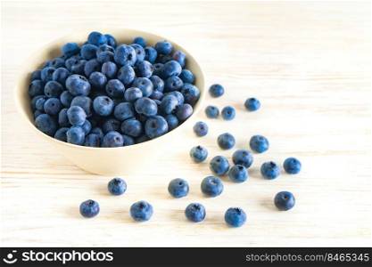 Fresh ripe organic blueberries in bowl on white wooden background with copy space for text. Fresh ripe organic blueberries in bowl on white wooden background