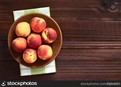 Fresh ripe peaches on clay plate, photographed overhead on dark wood with natural light. Fresh Ripe Peaches