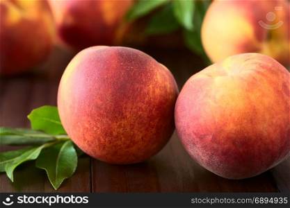 Fresh ripe peaches, photographed on dark wood with natural light (Selective Focus, Focus on the front of the front left peach). Fresh Ripe Peaches