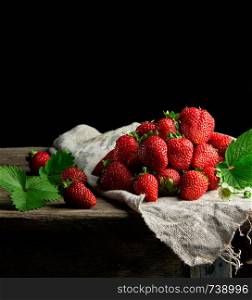 fresh ripe red strawberries on a gray linen napkin, wooden table, black background