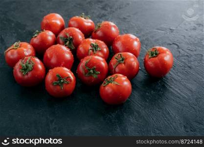 Fresh ripe red tomatoes on dark background with wet drops. Harvesting concept. Juicy raw vegetables for vegetarians. Heilroom plant. Freshness.