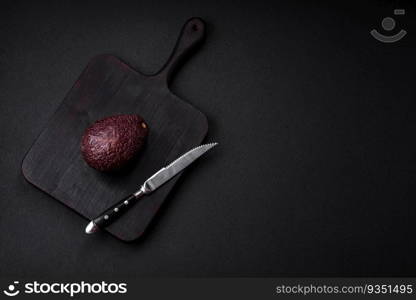 Fresh, ripe, soft brown colored avocado on a dark concrete background. Healthy cooking ingredients. Fresh, ripe, soft brown colored avocado on a dark concrete background