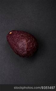 Fresh, ripe, soft brown colored avocado on a dark concrete background. Healthy cooking ingredients. Fresh, ripe, soft brown colored avocado on a dark concrete background