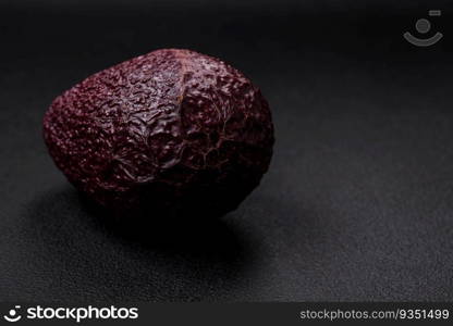 Fresh, ripe, soft brown colored avocado on a dark concrete background. Healthy cooking ingredients. Fresh, ripe, soft brown colored avocado on a dark concrete background