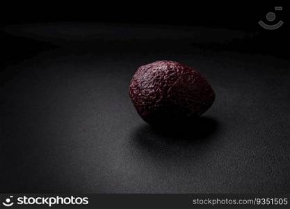 Fresh, ripe, soft brown colored avocado on a dark concrete background. Healthy cooking ingredients. Fresh, ripe, soft brown colored avocado on a dark concrete background