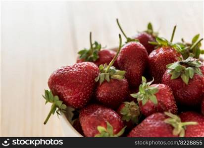 Fresh ripe strawberries in a bowl on a wooden table