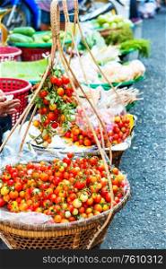 Fresh ripe tomatoes in wicker baskets at traditional asian street market