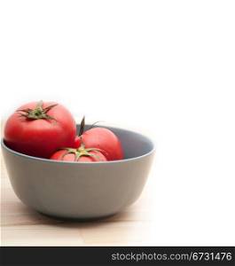 fresh ripe tomatoes on a blue bowl over pine wood table