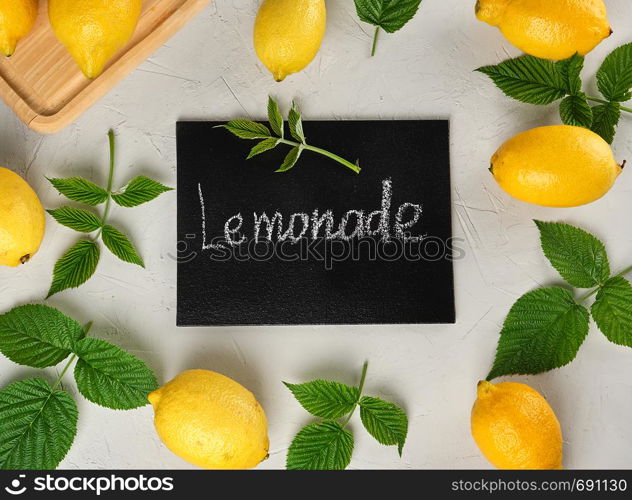 fresh ripe whole yellow lemons and black frame with an inscription lemonade, ingredients for making a drink, gray background