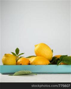 fresh ripe whole yellow lemons on a blue wooden board, ingredients for making summer drinks, copy space