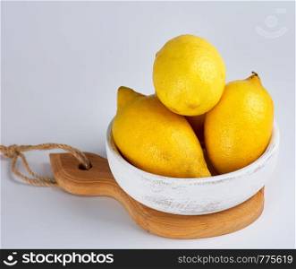 fresh ripe whole yellow lemons on a wooden board, ingredients for making summer drinks