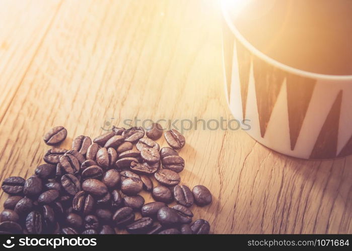 Fresh roasted coffee beans and mug on wooden table, background texture