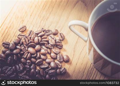 Fresh roasted coffee beans and mug on wooden table, background texture