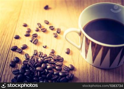Fresh roasted coffee beans and mug on wooden table, background texture
