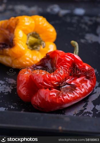 Fresh roasted red and yellow peppers over dark background, selective focus
