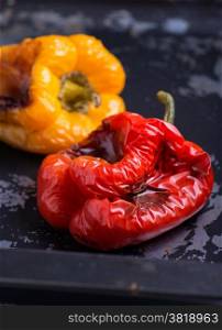Fresh roasted red and yellow peppers over dark background, selective focus