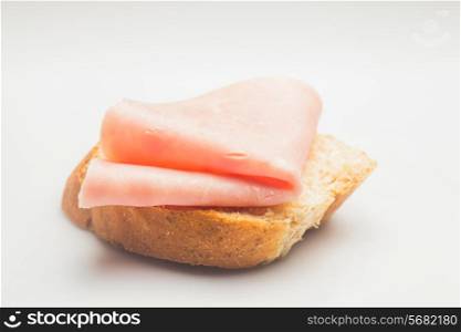 Fresh rolled ham slice and breadon a white plate close up