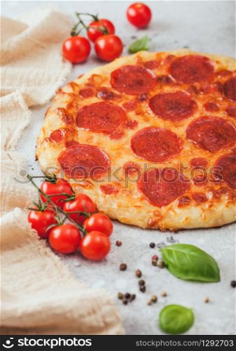 Fresh round baked Pepperoni italian pizza with tomatoes with basil on light kitchen table background. Space for text