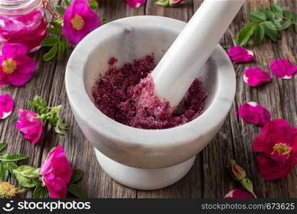 Fresh Rugosa rose flowers crushed with cane sugar in a marble mortar