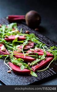 Fresh salad from beetroot, cheese and rocket salad on black wood background