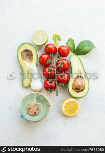 Fresh salad ingredients : halves avocado, tomatoes, lemon and olives oil on a white background. Top view. Vegetarian food. Healthy eating