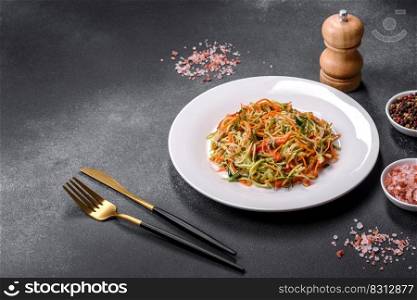 Fresh salad of sliced thin strips of carrot and zucχni on a concrete background. Ve≥tarian cuisi≠. Fresh salad of sliced thin strips of carrot and zucχni on a concrete background