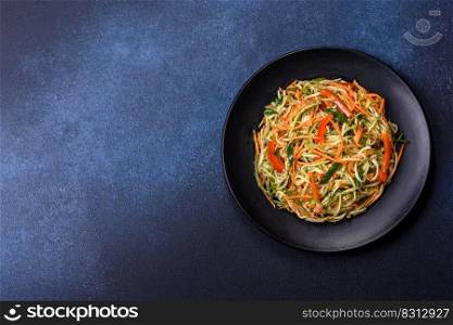 Fresh salad of sliced thin strips of carrot and zucchini on a concrete background. Vegetarian cuisine. Fresh salad of sliced thin strips of carrot and zucchini on a concrete background