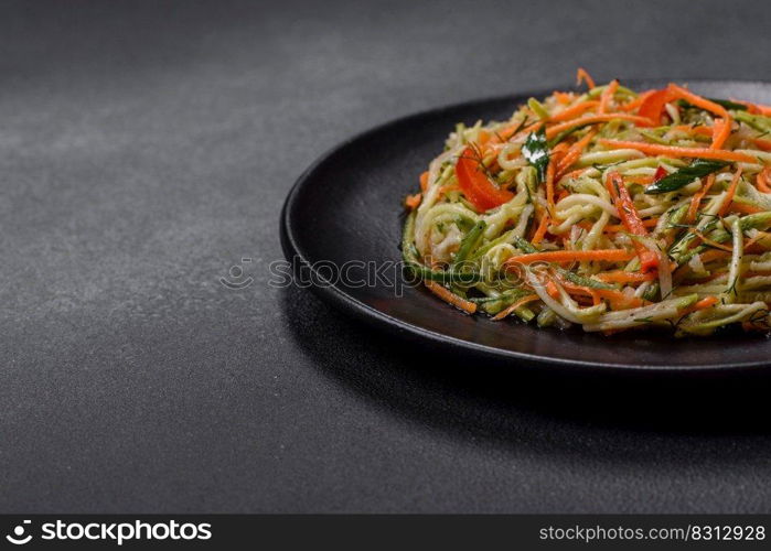 Fresh salad of sliced thin strips of carrot and zucchini on a concrete background. Vegetarian cuisine. Fresh salad of sliced thin strips of carrot and zucchini on a concrete background