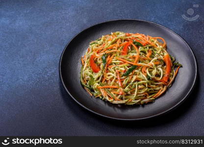 Fresh salad of sliced thin strips of carrot and zucchini on a concrete background. Vegetarian cuisine. Fresh salad of sliced thin strips of carrot and zucchini on a concrete background