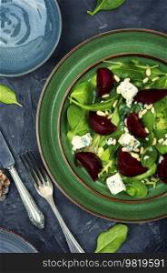 Fresh salad with beets, blue cheese, herbs and pine nuts on the green plate. Healthy food. Meatless salad with beet, cheese and pine nuts,top view
