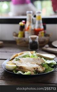 Fresh salad with chicken breast on wood background