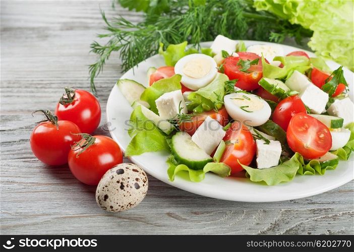 Fresh salad with quail eggs, cherry tomato, cucumber and lettuce on a wooden background