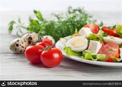 Fresh salad with quail eggs, cherry tomato, cucumber and lettuce on a wooden table