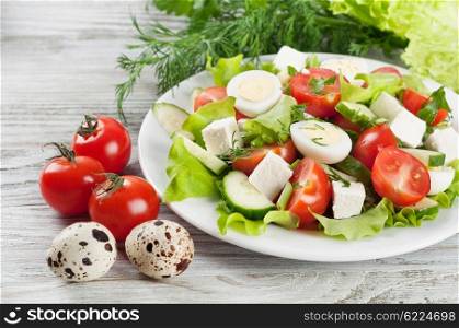 Fresh salad with quail eggs, cherry tomato, cucumber and lettuce on a wooden table.