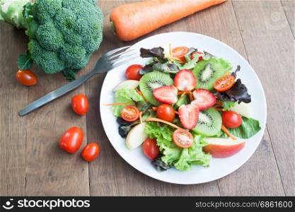 Fresh salad with strawberries, kiwi, tomatoes and apples on white plate