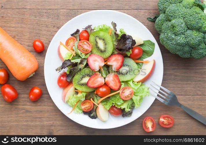 Fresh salad with strawberries, kiwi, tomatoes and apples, top view