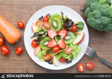 Fresh salad with strawberries, kiwi, tomatoes and apples, top view