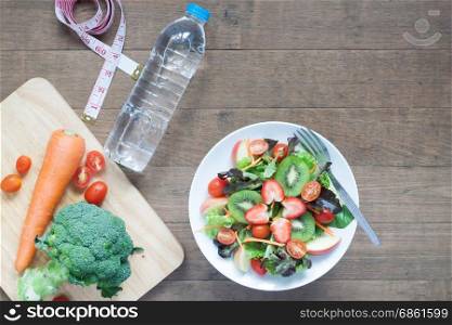 Fresh salad with strawberries, kiwi, tomatoes and apples withbottle of water, Diet and Fitness concept