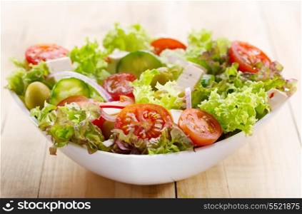 fresh salad with vegetables and greens on wooden table