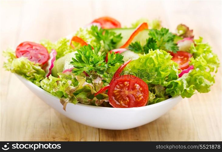 fresh salad with vegetables and greens on wooden table