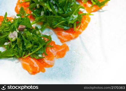 fresh salmon carpaccio sushi sashimi with arugula rocket salad and caper on top