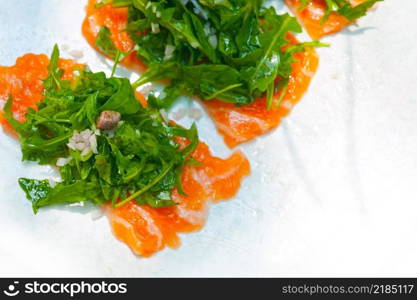 fresh salmon carpaccio sushi sashimi with arugula rocket salad and caper on top