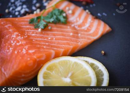 Fresh salmon fillet on dark background / Close up of raw salmon fish seafood with lemon herbs and spices