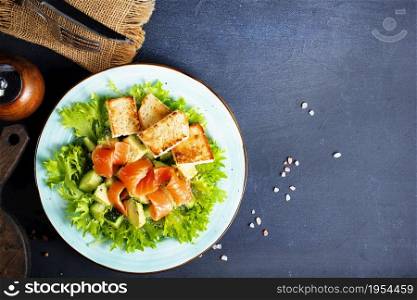 fresh salmon fish with green lettuce and vegetables, fresh salad with greens, salmon and croutons