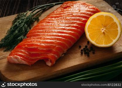 Fresh salmon piece on wooden cooking board with vegetables. Fresh salmon piece on wooden board